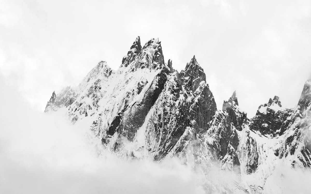Dramatic black and white mountain peaks emerging from clouds with sharp granite spires and deep tonal contrast