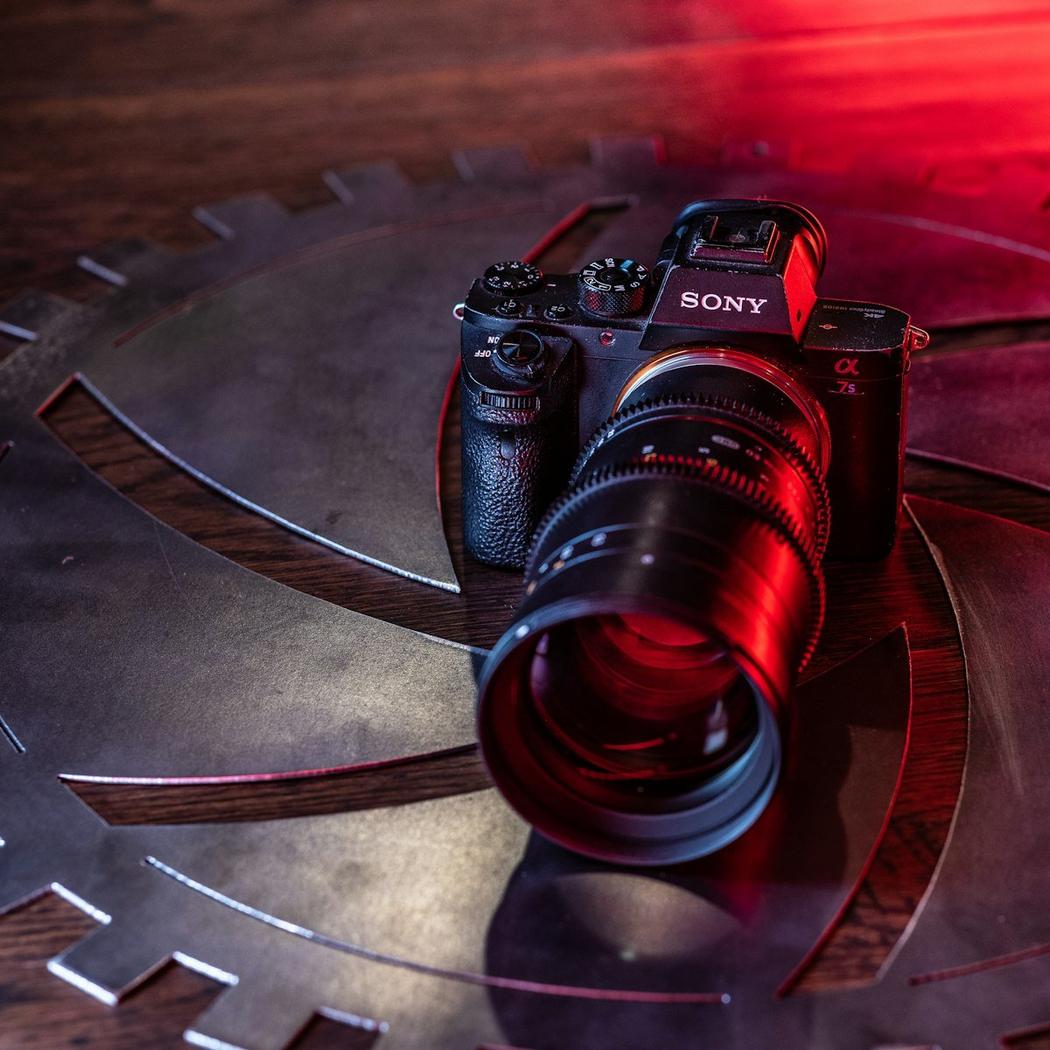 Modern Sony Alpha mirrorless camera body with professional lens in dramatic red accent lighting on dark surface