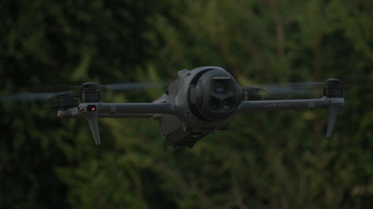 DJI Mavic 4 Pro with Hasselblad camera in flight against lush green forest canopy