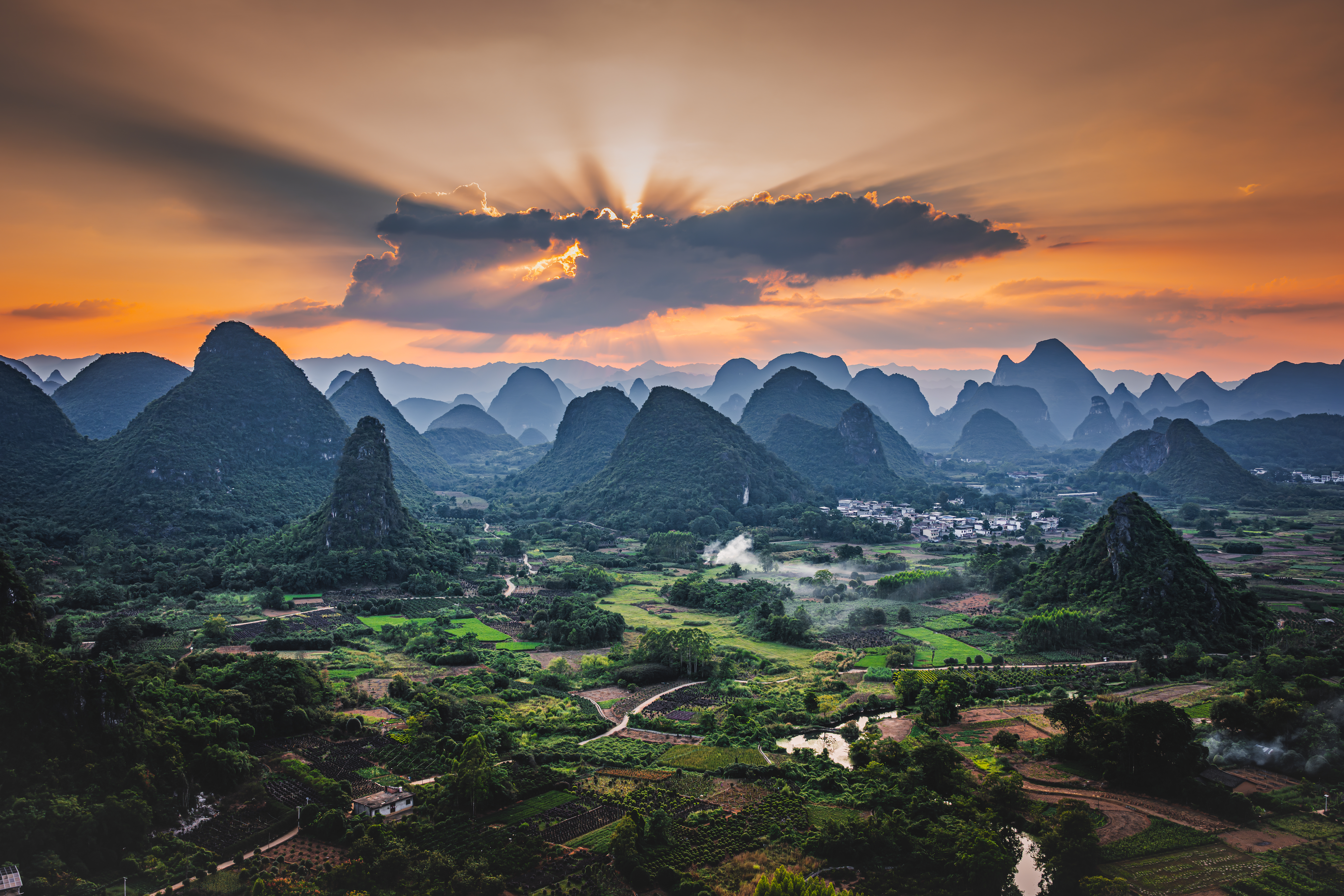 Sunburst through clouds over karst landscape