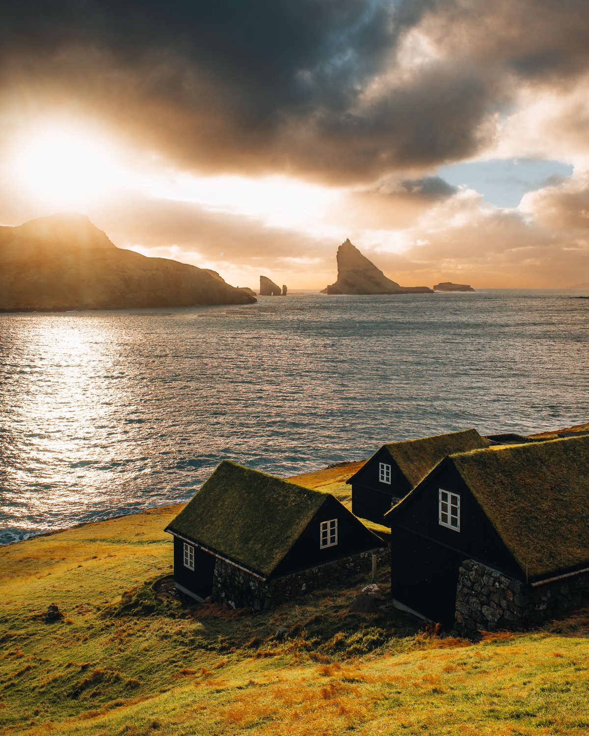 Bour village with traditional turf-roofed houses and sea stacks in the distance
