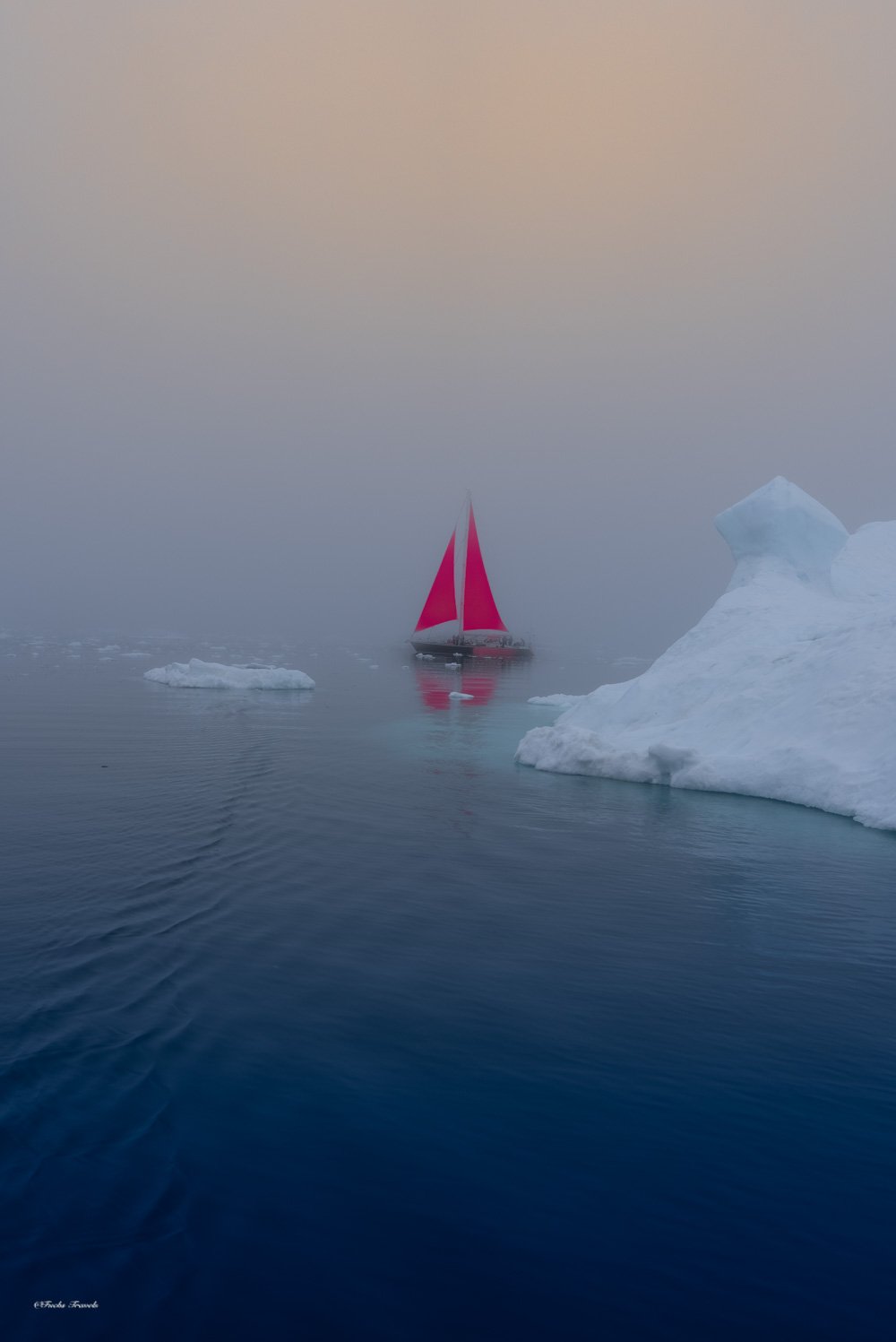 Red sailboat emerging from thick fog near an iceberg, creating an ethereal and otherworldly atmosphere