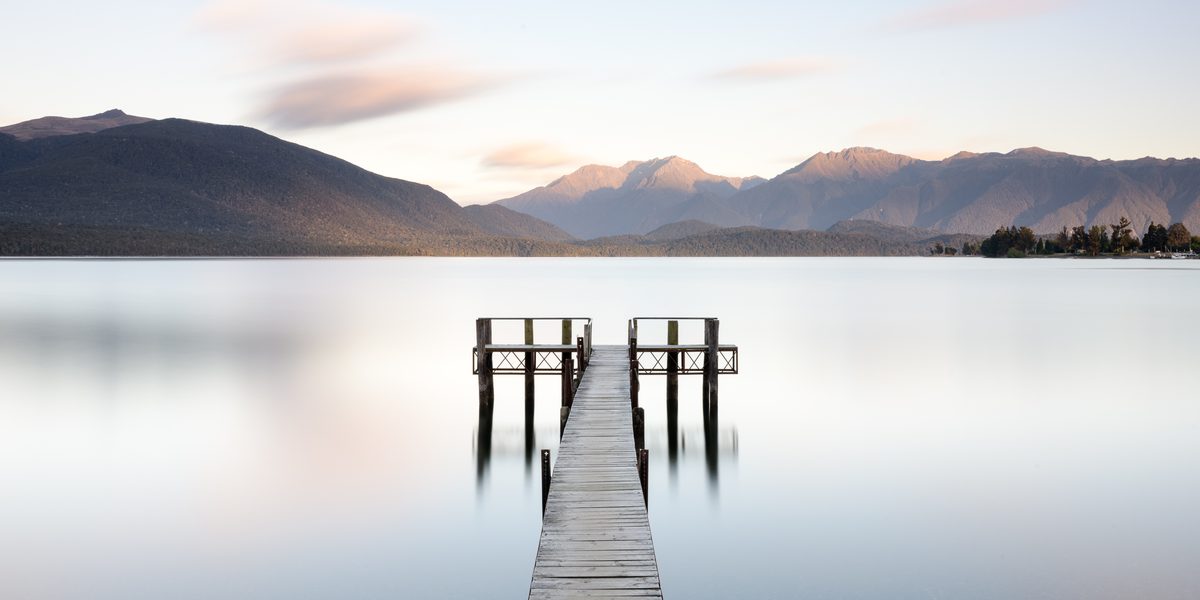 Lake Te Anau at golden hour with mountains reflected in still water