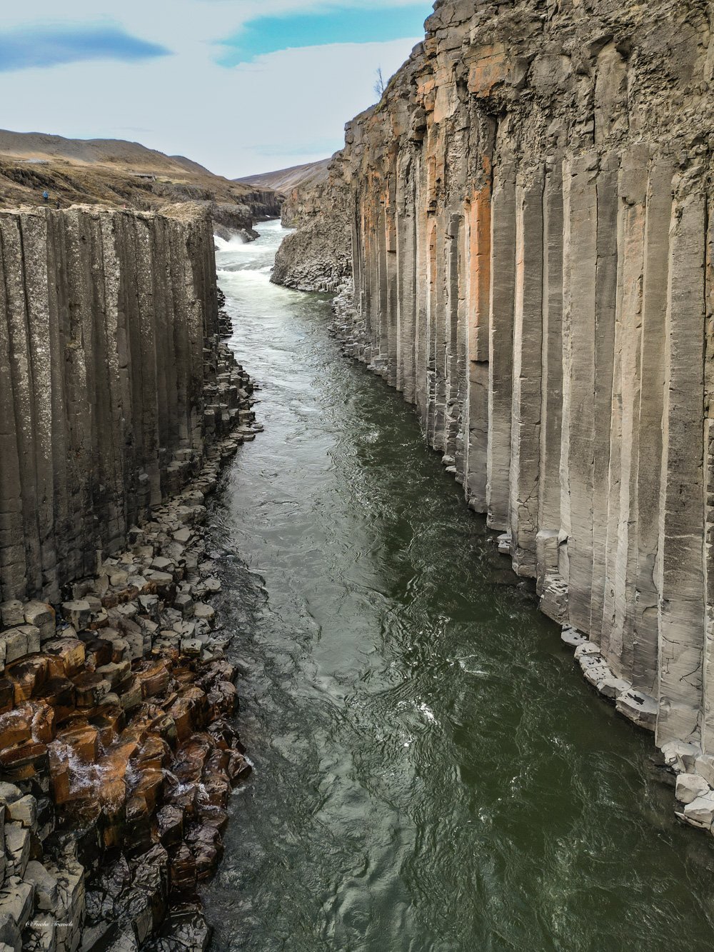 Stuðlagil basalt column canyon with glacial river flowing between towering hexagonal columns